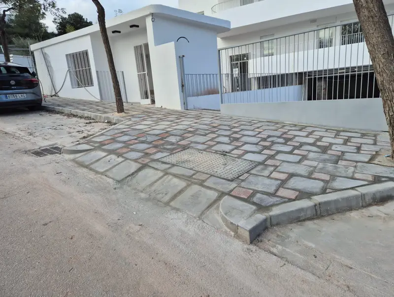 Calle adoquinada terminada frente a viviendas blancas