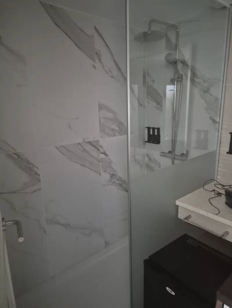 Baño con revestimiento de mármol y mampara de vidrio