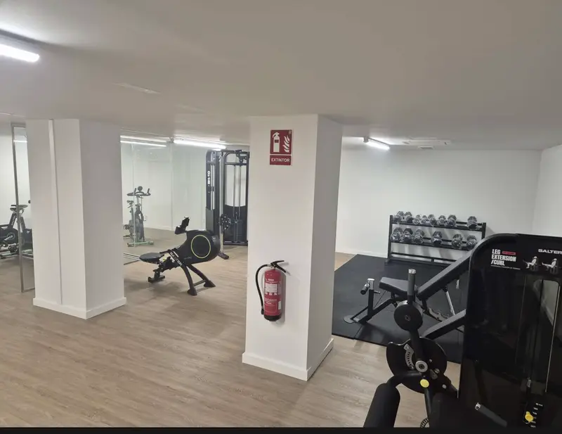 Gimnasio de la zona común con máquinas y espejos
